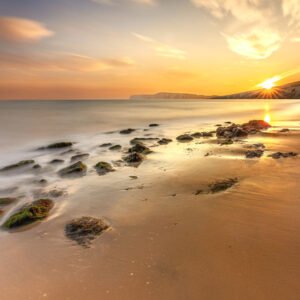 Golden sunset over Compton Bay on the Isle of Wight with silky long-exposure waves and sandy beach.