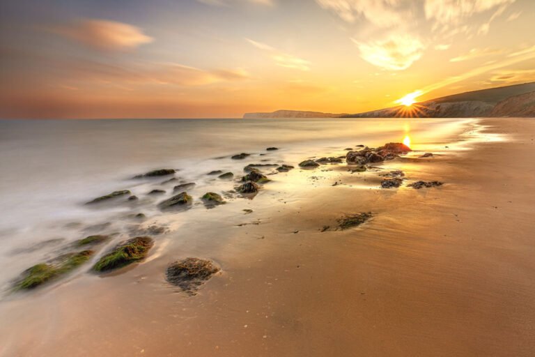 Golden sunset over Compton Bay on the Isle of Wight with silky long-exposure waves and sandy beach.